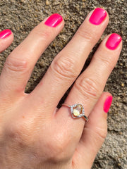 Hand wearing a ring with a diamond shaped cintrine gemstone against a textured background 