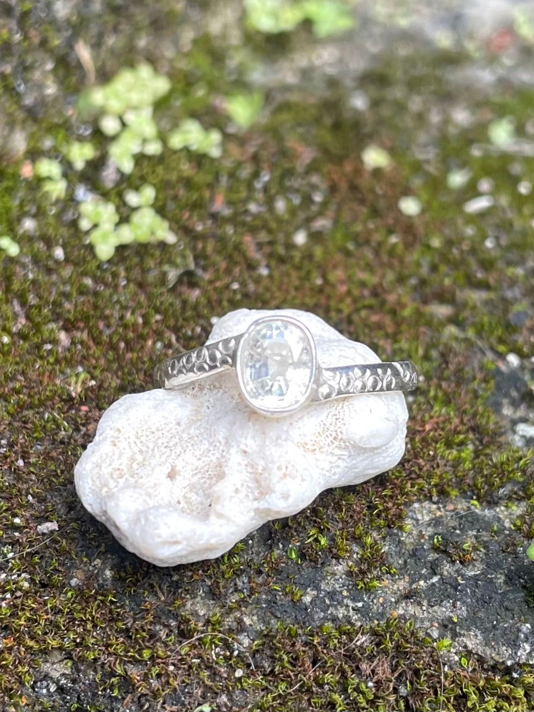 Silver and white sapphire ring on beautiful engraved band sitting on a rock in Sri Lanka 