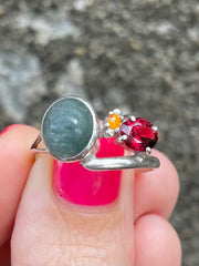 Close up of Indian Catseye, Yellow Quartz & Garnet Silver ring held by hand- Made In Sri Lanka - Kalumali Design