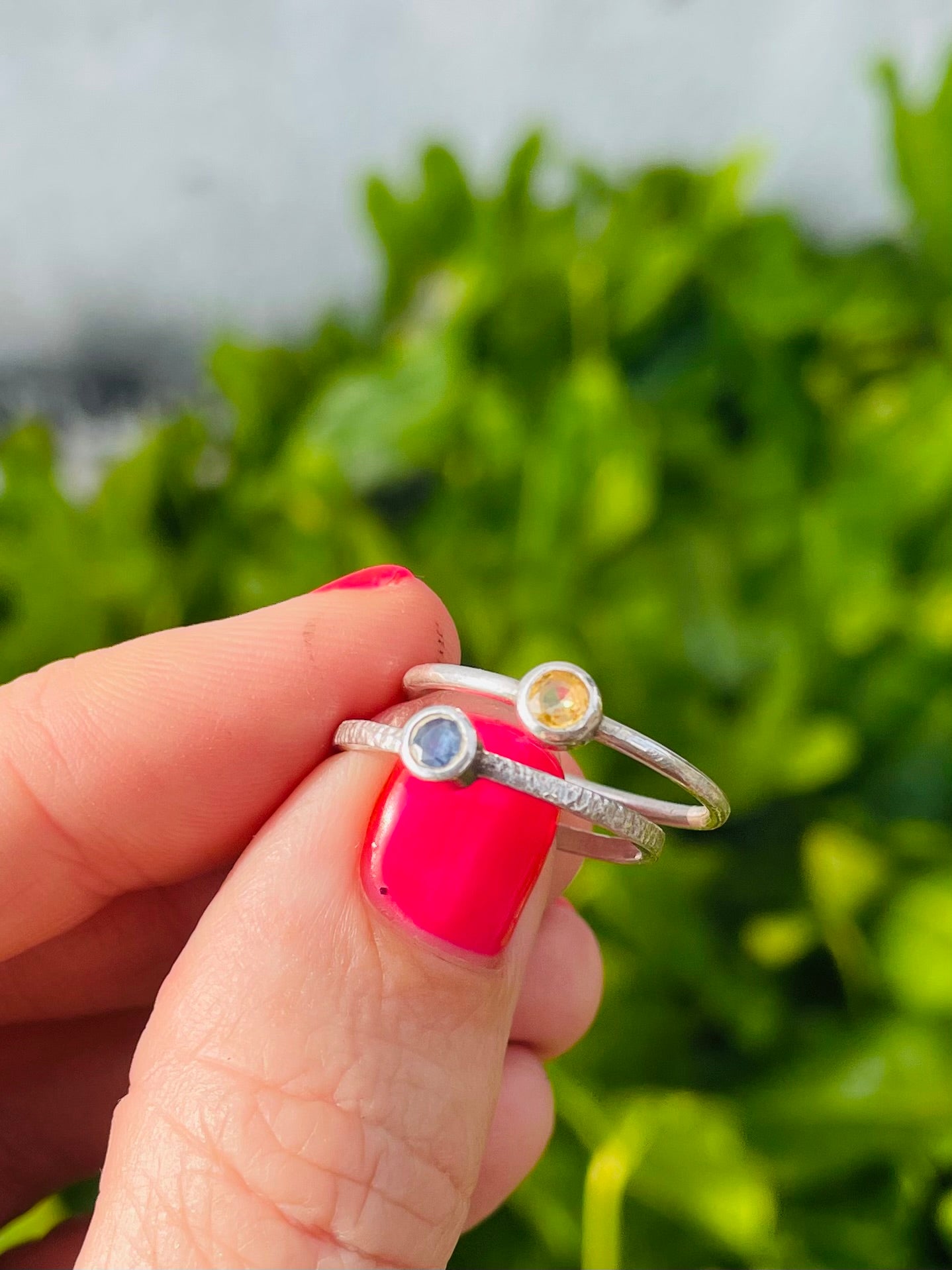 Hand holding 2 sterling silver rings sapphires