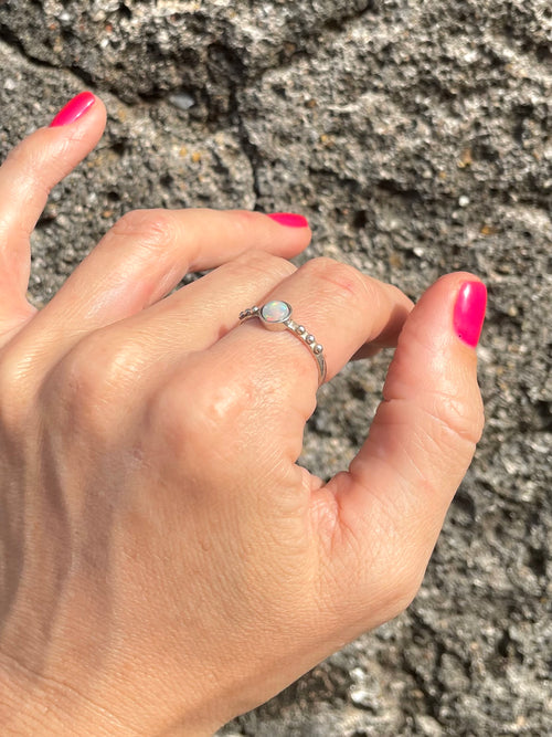 Hand wearing Sri Lankan opal and silver ring against stone